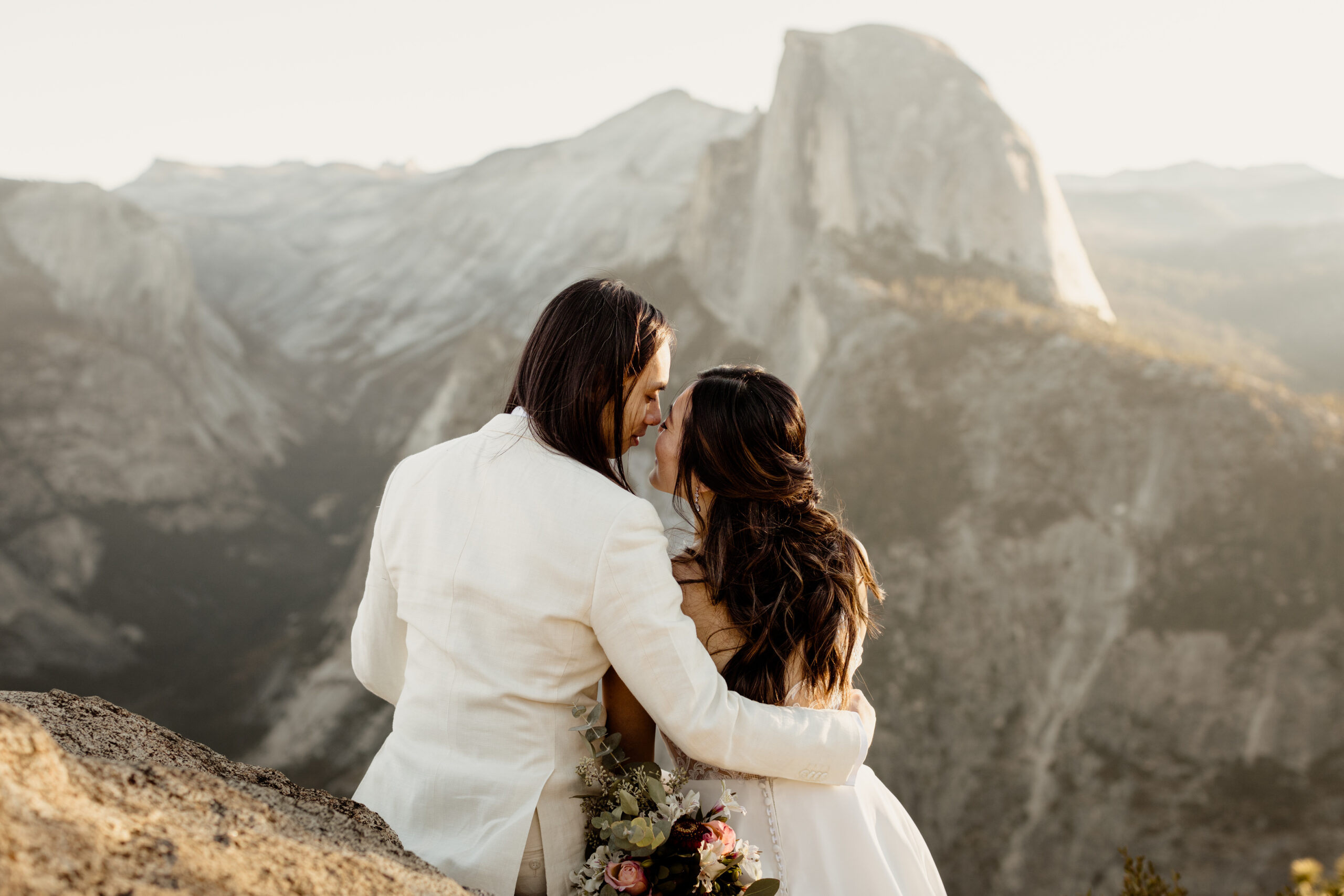Couples kisses with half dome in the background